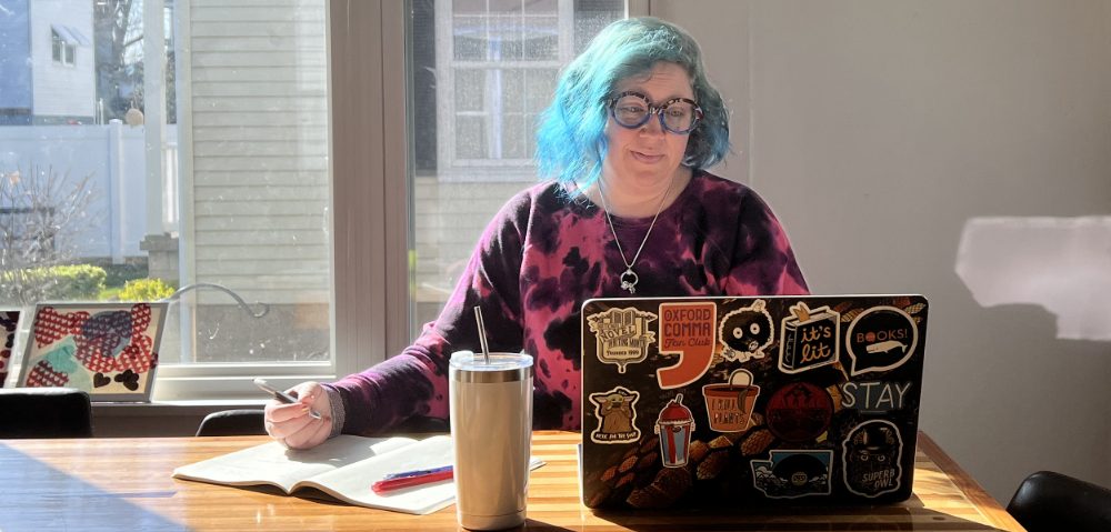 woman working at table with laptop pens notebook and cup working on business growth and business writing services