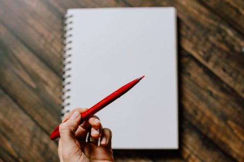 hand holding red pen for correcting grammar in copywriting